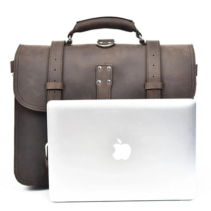 Dark brown leather messenger bag with laptop in white case featuring Apple logo