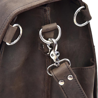 Brown leather bag strap close-up with silver key clip and round metal rings.