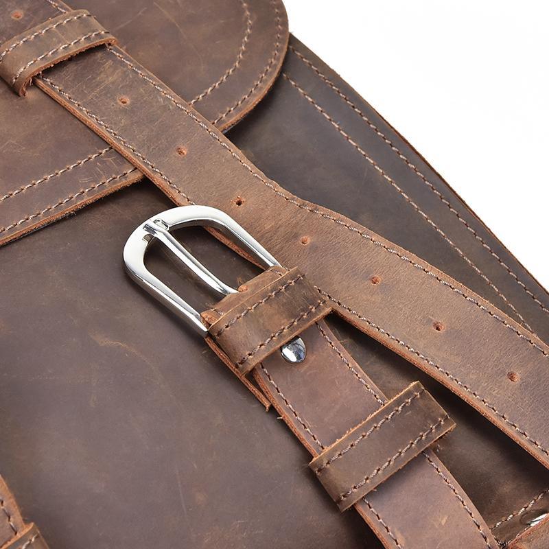 Brown leather strap detail with stitched edges and silver metal buckle hardware.