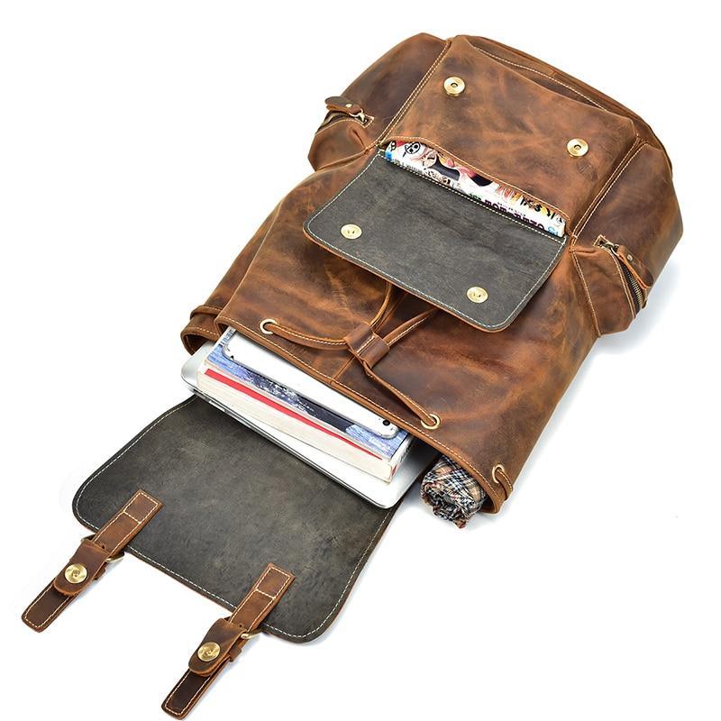 Brown vintage leather backpack laid open with multiple front pockets and snap tabs.