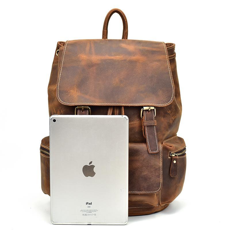 Brown vintage leather backpack with top flap; iPad tucked into front pocket.