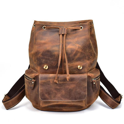 Brown drawstring backpack with metal eyelets, snap button flap, and adjustable straps