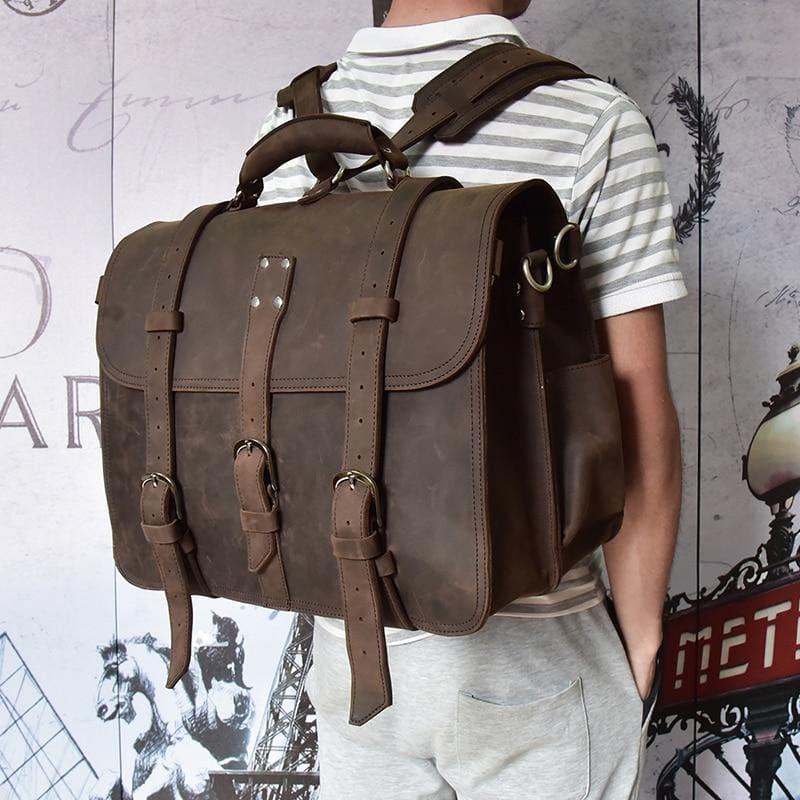 Dark brown leather messenger bag with flap and wide shoulder strap, worn on body