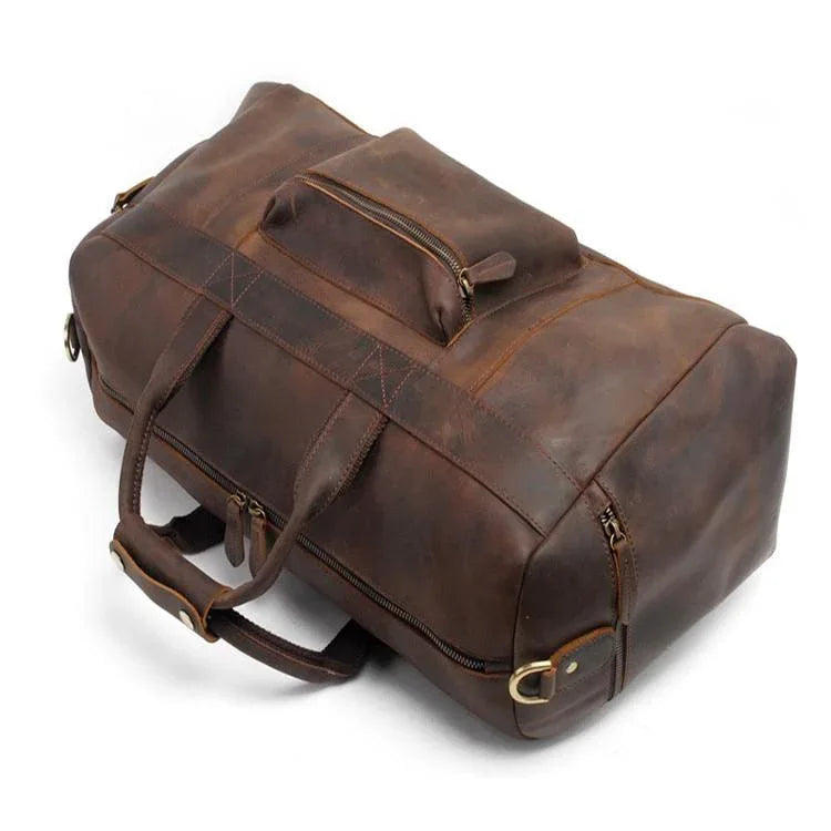 Brown leather duffle bag with side strap, stitched panels, and front zip pocket