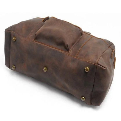 Brown leather duffle bag with reinforced sides and brass feet on the bottom