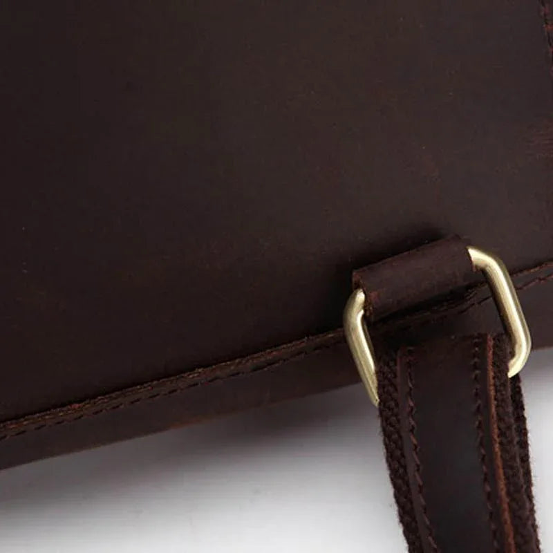 Leather strap attachment with brass-toned rings and visible stitching