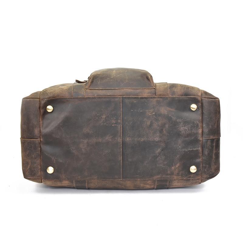 Brown leather duffle bag with snap strap detail and metal hardware, back view.