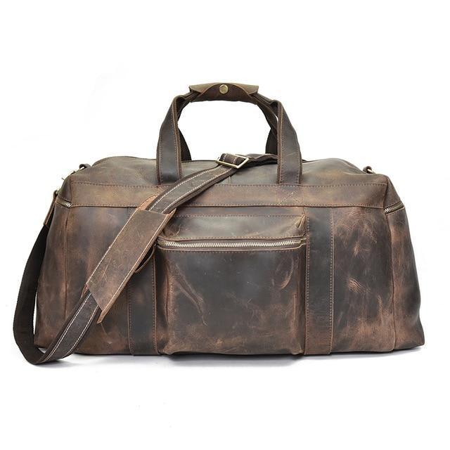 Brown leather duffle bag with crossbody strap, front zip compartment, and top handles.