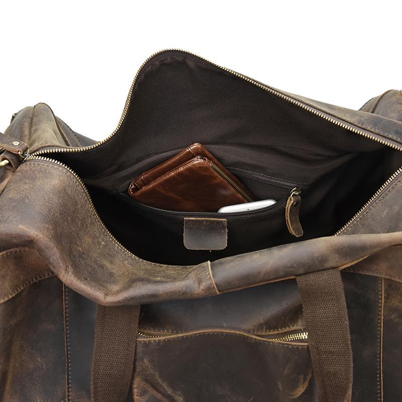 Open brown leather duffle bag showing interior zip pocket and lining.