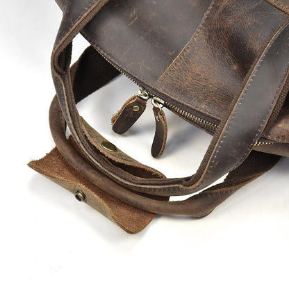 Leather duffle bag corner detail with strap attachments and metal buckles.