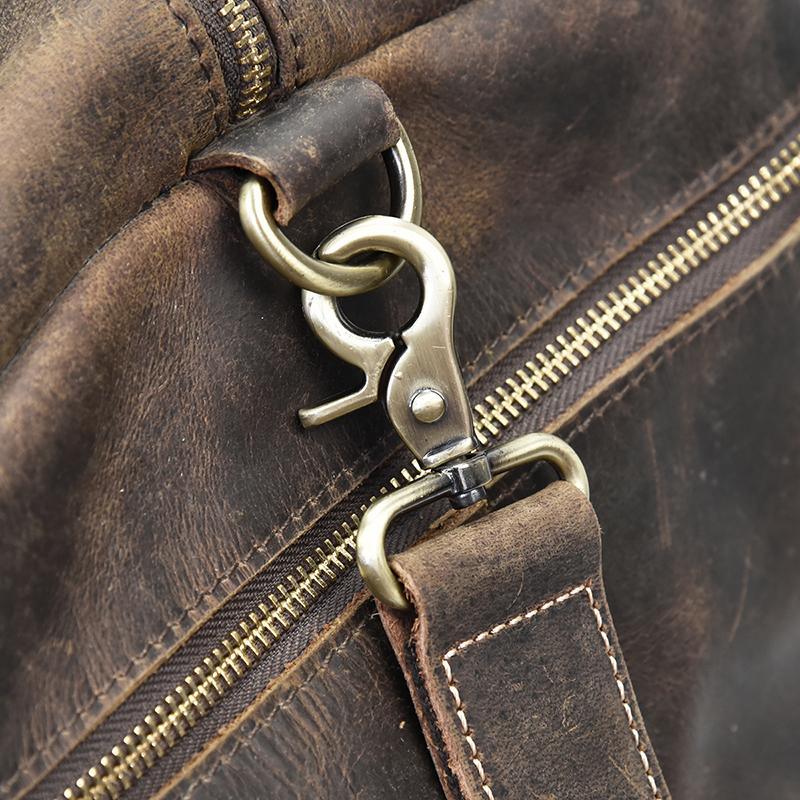 Distressed dark brown leather duffle bag close-up of metal D-ring and zipper pull
