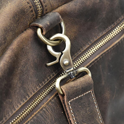 Distressed dark brown leather duffle bag close-up of metal D-ring and zipper pull