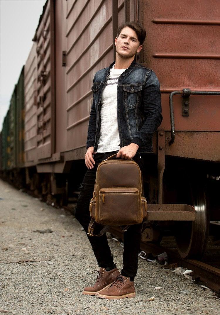 Brown leather vintage backpack worn cross-body with zipper front pocket