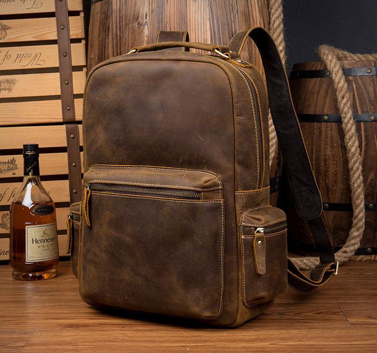 Brown leather vintage backpack with front zipper, side straps, and carry handle