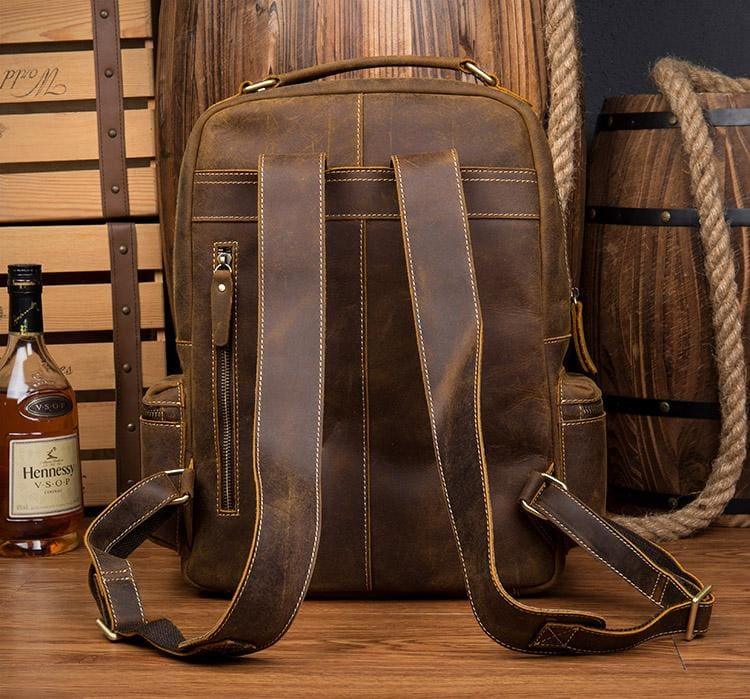 Brown leather backpack with multiple vertical front pockets and crossbody straps.
