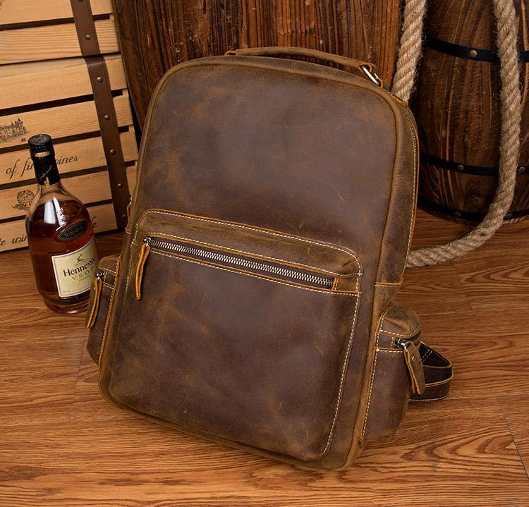 Brown leather vintage backpack with front zipper pocket and side accessory strap
