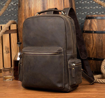 Dark brown leather vintage backpack with front pocket, zipper trim, and shoulder strap