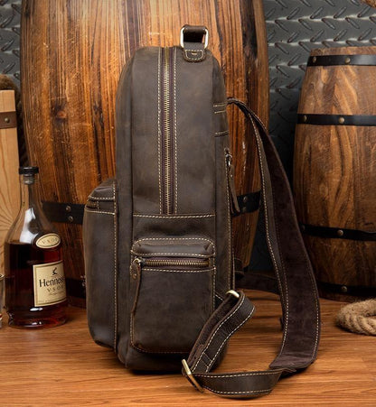 Dark brown leather backpack with vertical front zipper and side strap, shown in profile.