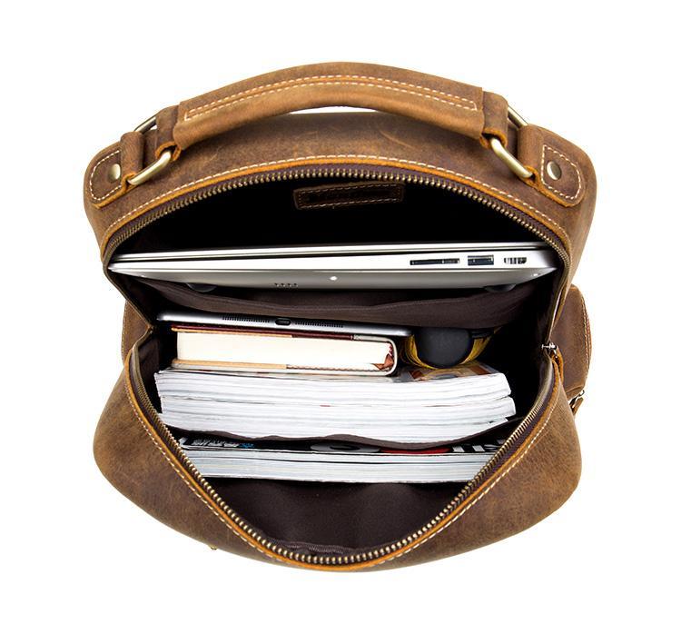 Brown leather vintage backpack open at top showing lined interior and zipper closure