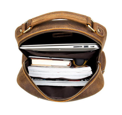 Brown leather vintage backpack open at top showing lined interior and zipper closure