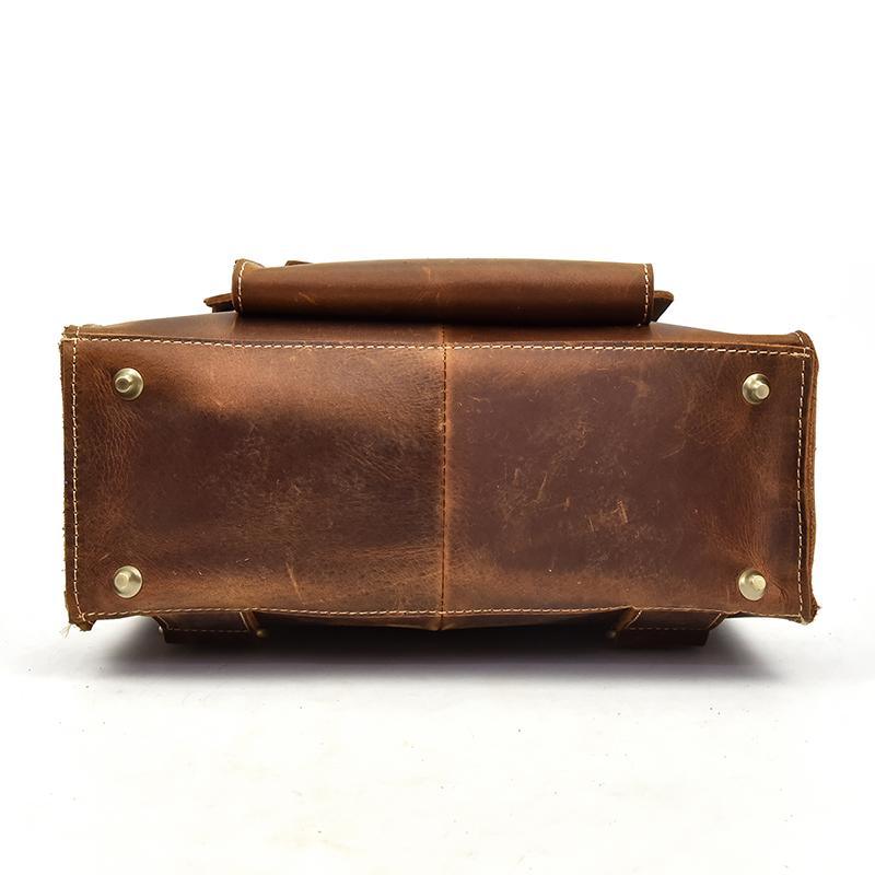 Brown leather backpack bottom/side view with metal rivets and rolled top edge