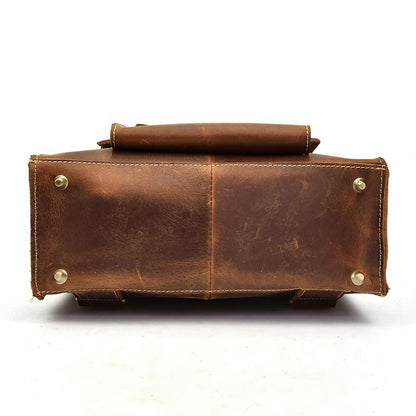 Brown leather backpack bottom/side view with metal rivets and rolled top edge