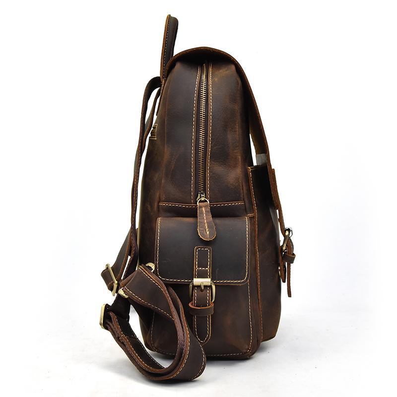 Brown leather backpack back view with zipper, front latch, and adjustable shoulder strap