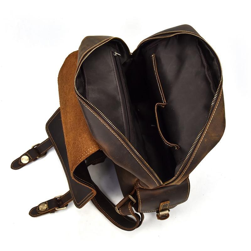 Brown leather backpack opened to reveal dark lined interior with dual zippers