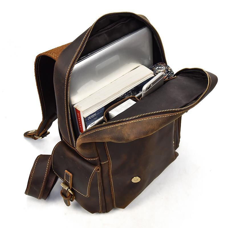 Brown leather backpack open with stored books and documents, zip top closure