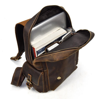 Brown leather backpack open with stored books and documents, zip top closure