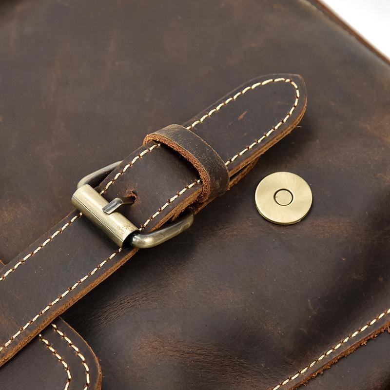 Leather backpack flap strap with brass-tone buckle and contrasting stitched edges