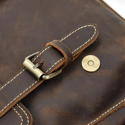 Leather backpack flap strap with brass-tone buckle and contrasting stitched edges