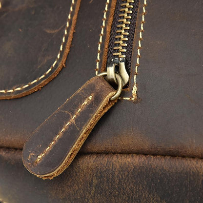 Leather backpack zipper with metal pull and stitched brown leather tab