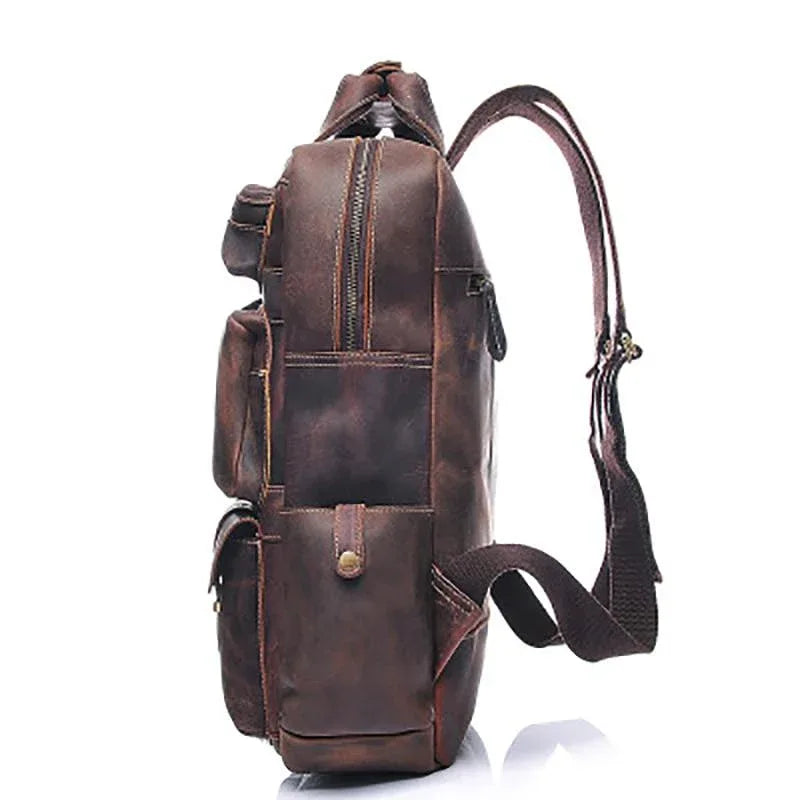 Brown leather backpack with long side strap and front utility pockets.