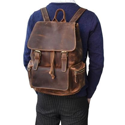Brown leather backpack worn on back with front flap, buckles, and side zip pocket