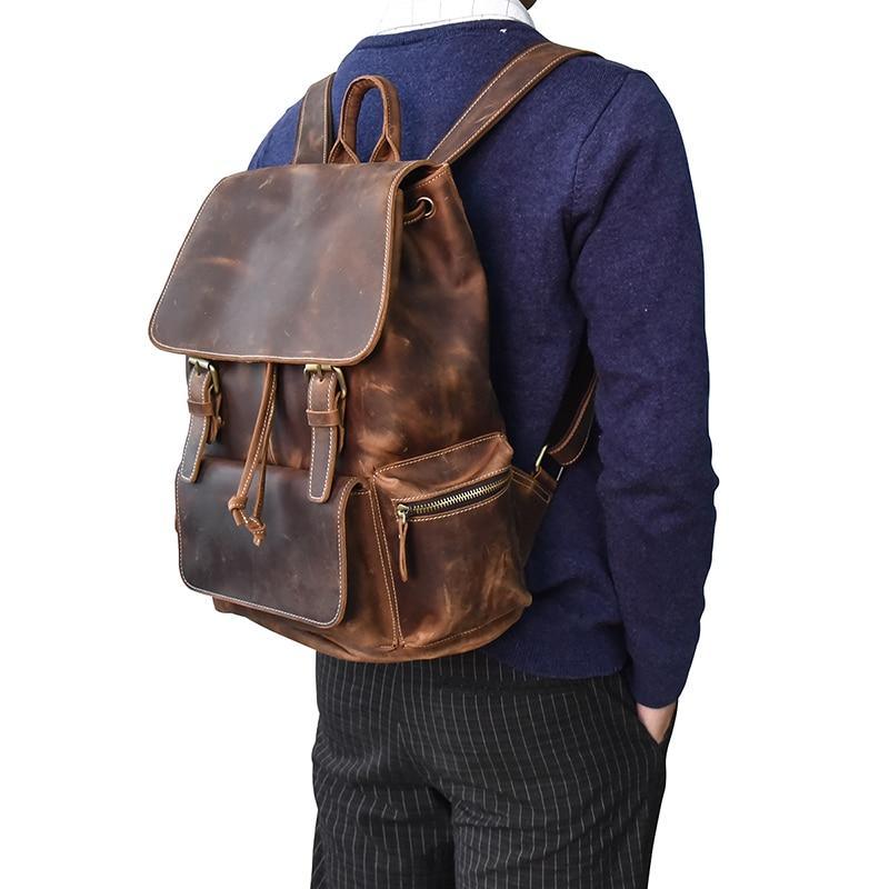 Brown leather backpack worn on back with flap, buckles, and adjustable shoulder straps