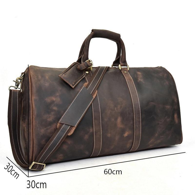 Dark leather duffel bag with crossbody strap, brass-tone buckles, and front details