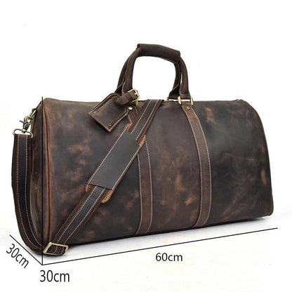 Dark leather duffel bag with crossbody strap, brass-tone buckles, and front details