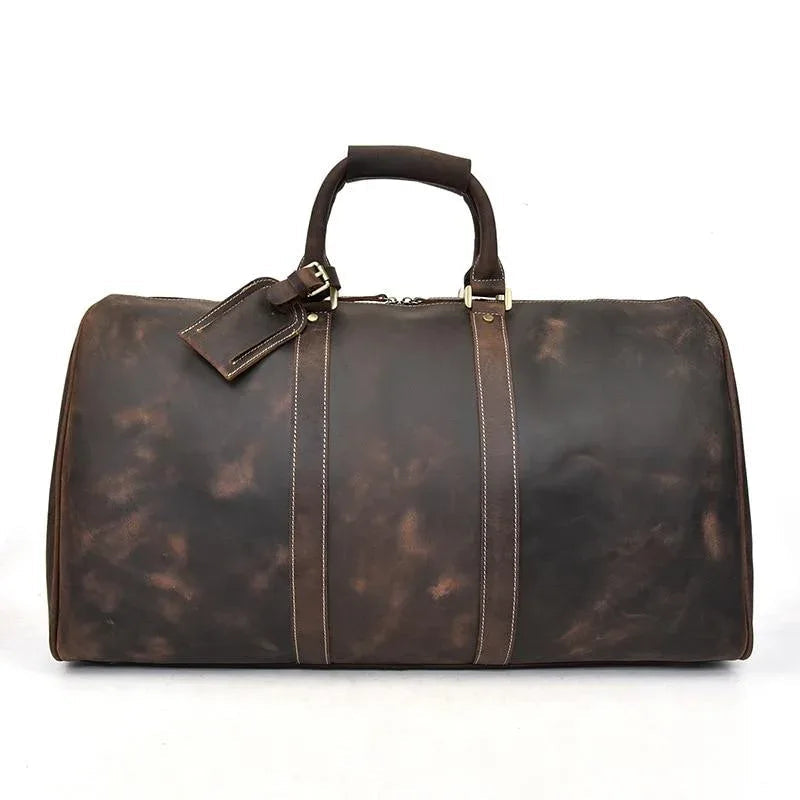 Dark brown leather duffle bag with top handles, front leather nameplate, and stitched seams.