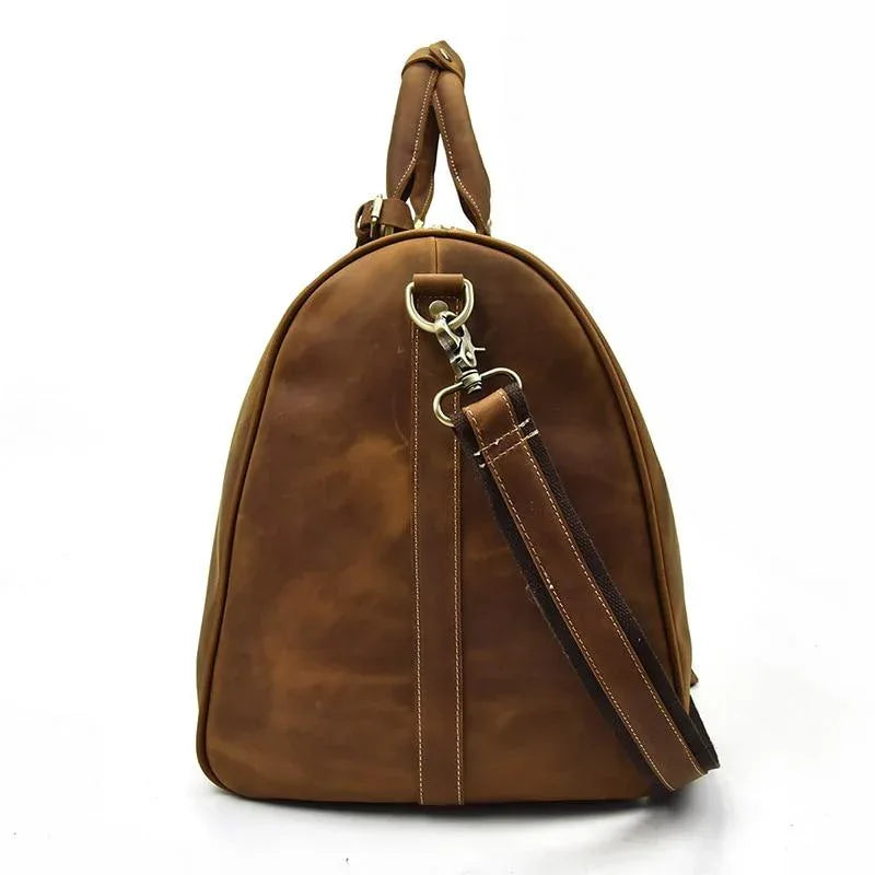 Tan leather duffle bag with curved handles and detachable shoulder strap, metal rings.