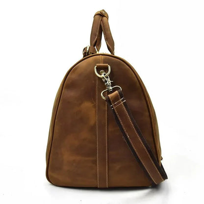Tan leather duffle bag with curved handles and detachable shoulder strap, metal rings.