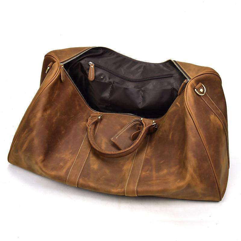 Brown leather duffle bag with zipper top, stitched panels, and front pocket.