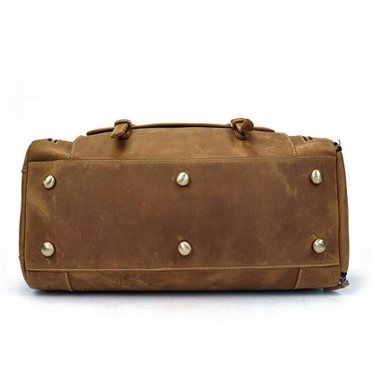 Handmade leather duffle bag in brown with metal stud accents on the front panel