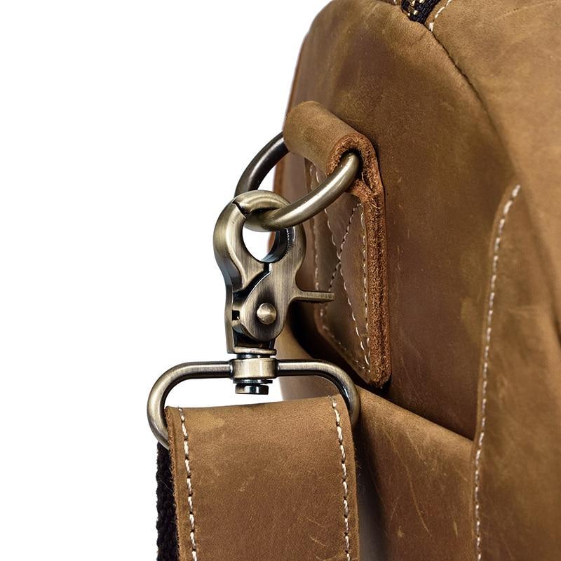 Leather duffle bag hardware close-up with D-ring and snap strap tab