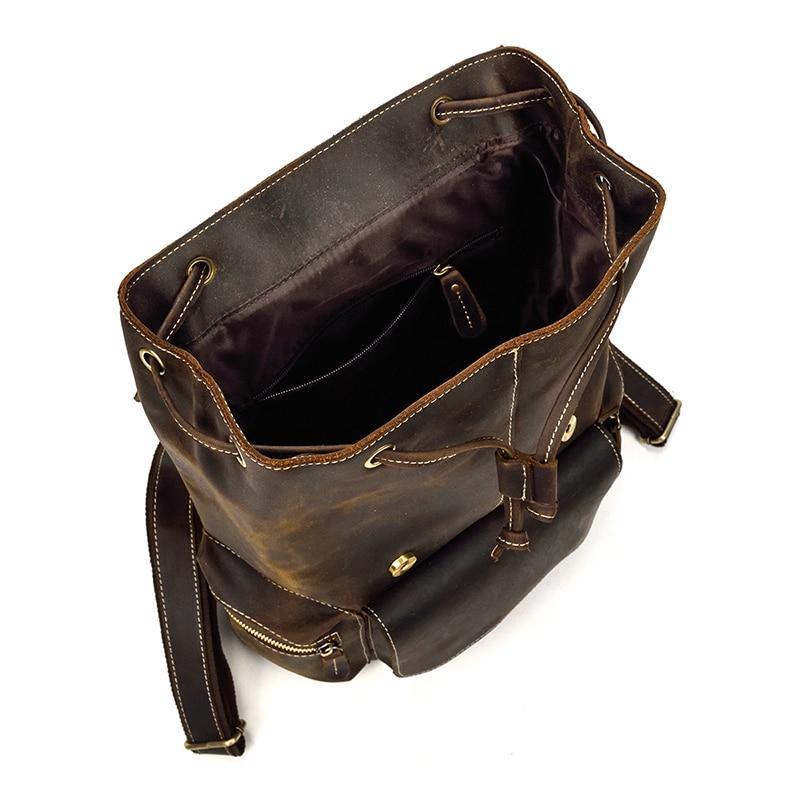 Vintage leather backpack with open interior and shoulder strap, dark brown leather