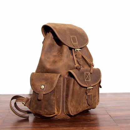 Brown leather rucksack side view with small front pocket and flap buckle details
