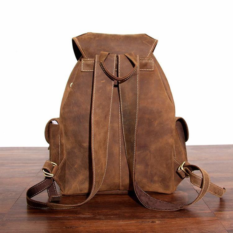 Brown leather rucksack with top flap, stitched vertical panels, and adjustable straps