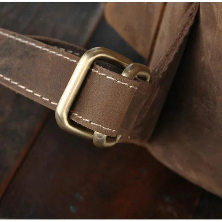 Close-up of leather rucksack strap with brass buckle and stitched tab