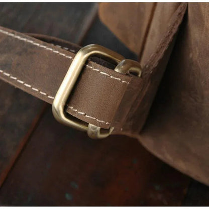 Close-up of leather rucksack strap with brass buckle and stitched tab