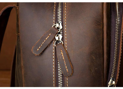 Brown leather backpack close-up of zipper pull and stitched leather tabs